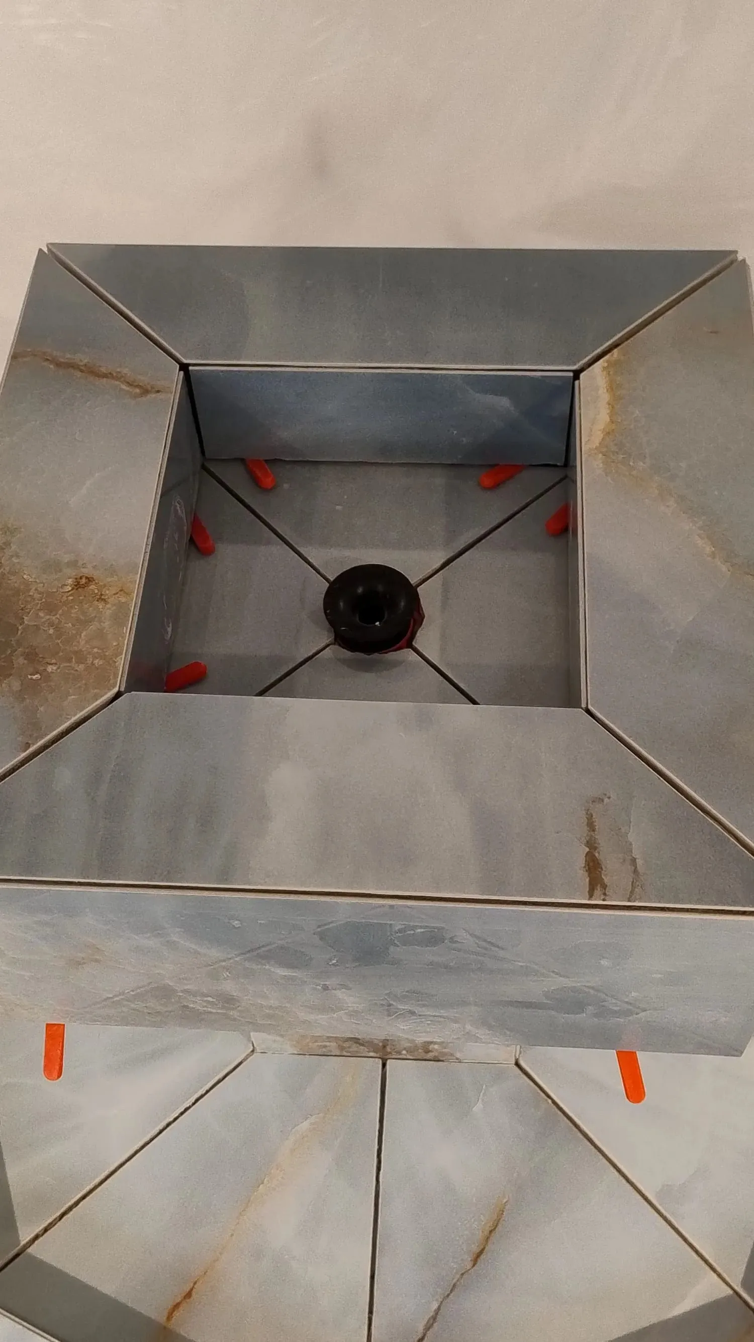 Blick von oben in den Brunnenkopf während der Verfliesung: auf Gehrung geschnittene Platten, mit Keilen ausgerichtet
