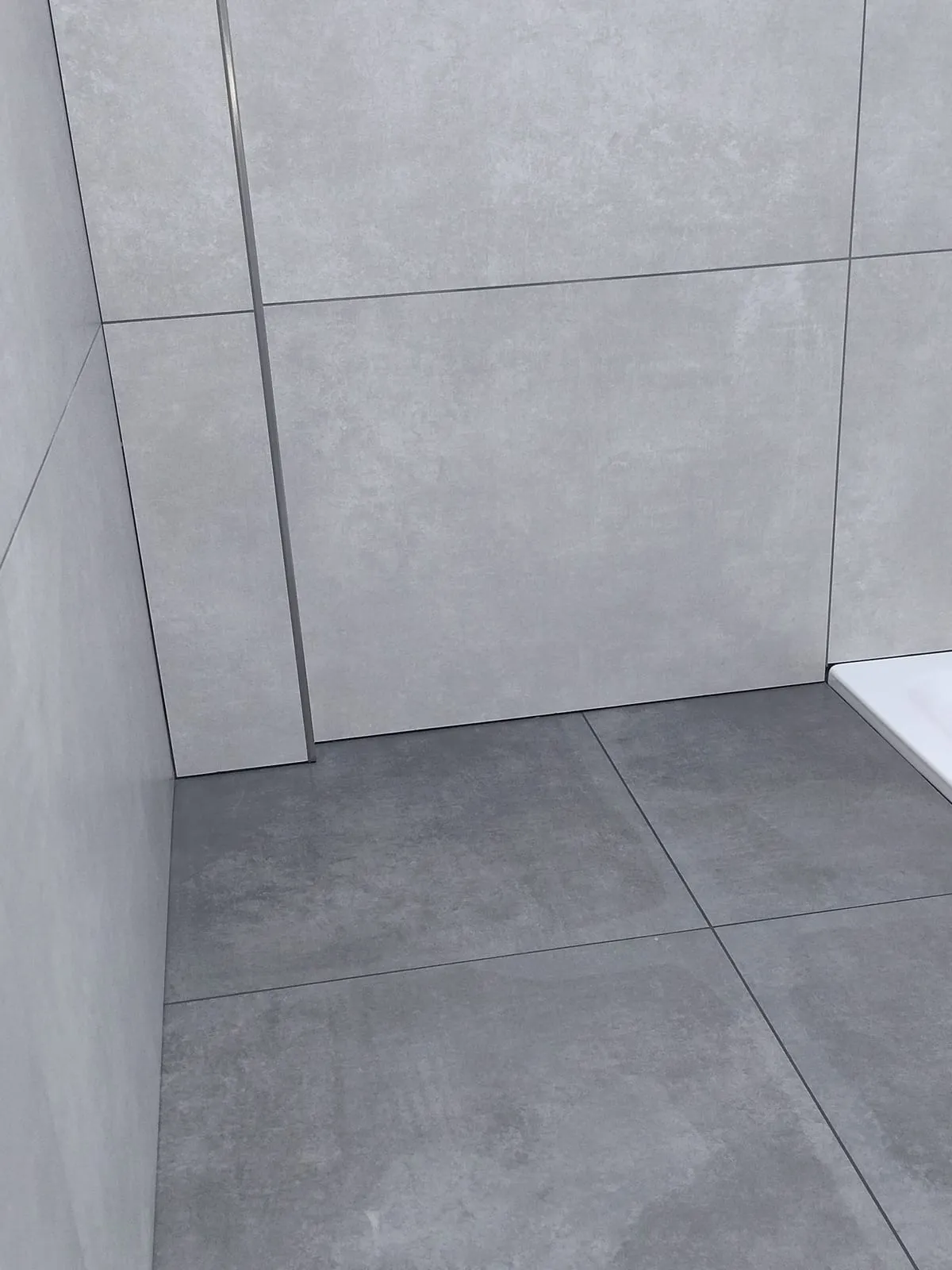 Eckdetail: Betonoptik-Platten an Wand und Boden, mit Kantenprofil abgeschlossen