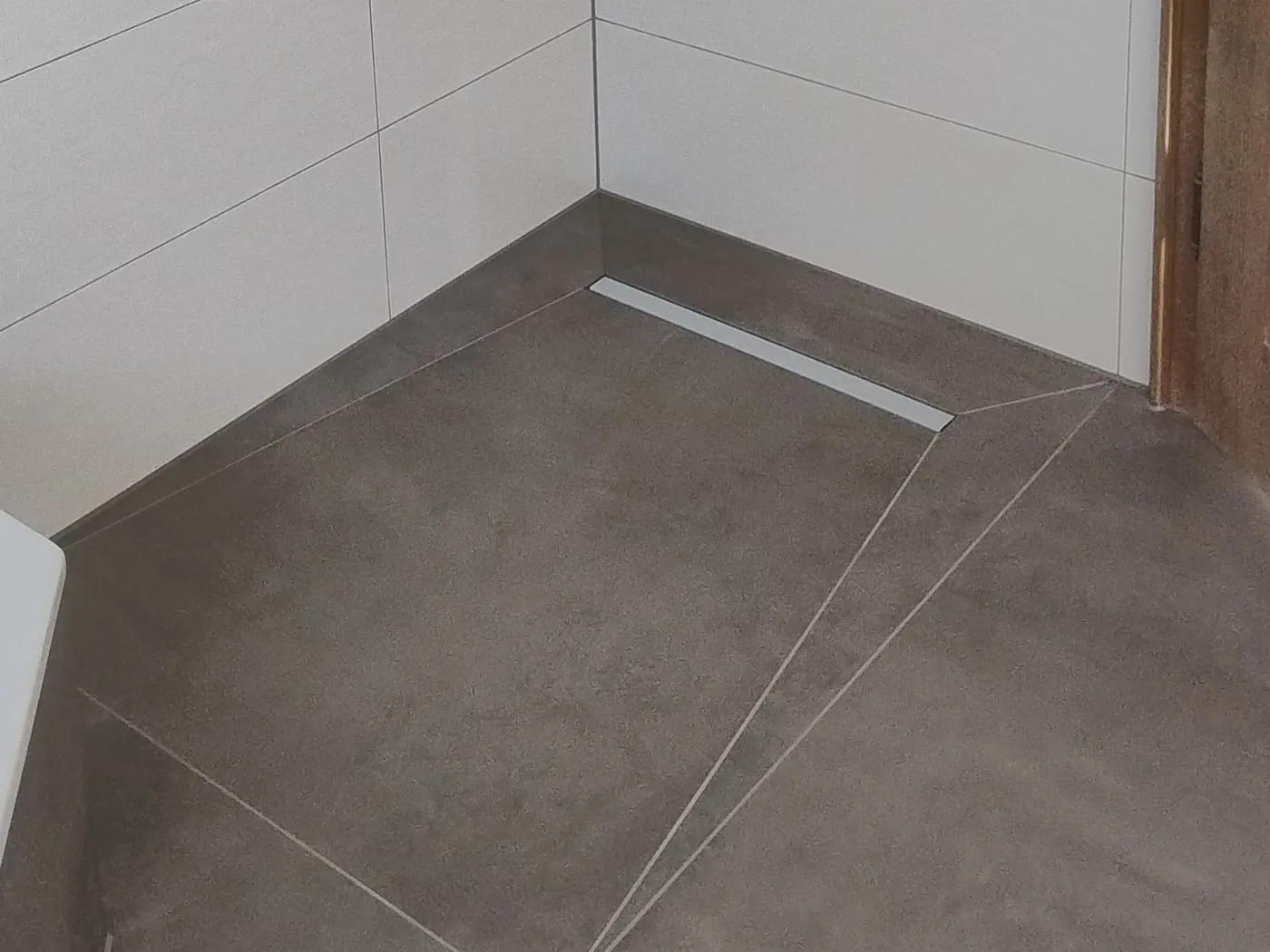 Bodengleiche Dusche: Duschrinne am Wandanschluss und Gefälleschnitte in graubraunen Großformatplatten