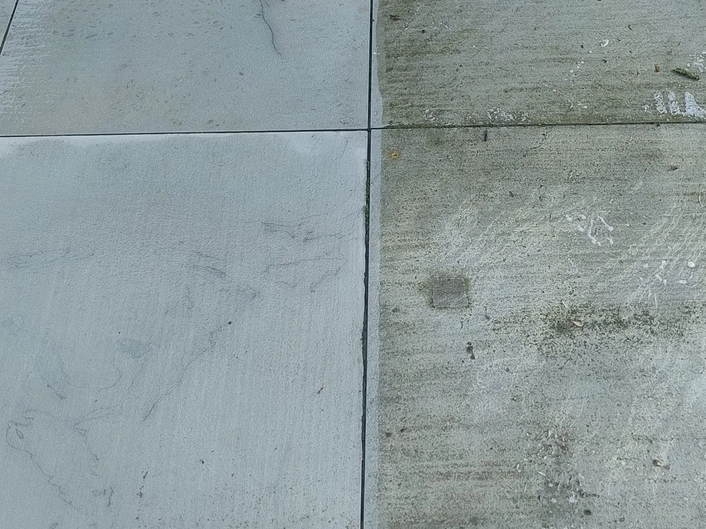 Terrassenplatten zur Hälfte gereinigt — links aufbereitet, rechts mit Grünbelag und Verschmutzung